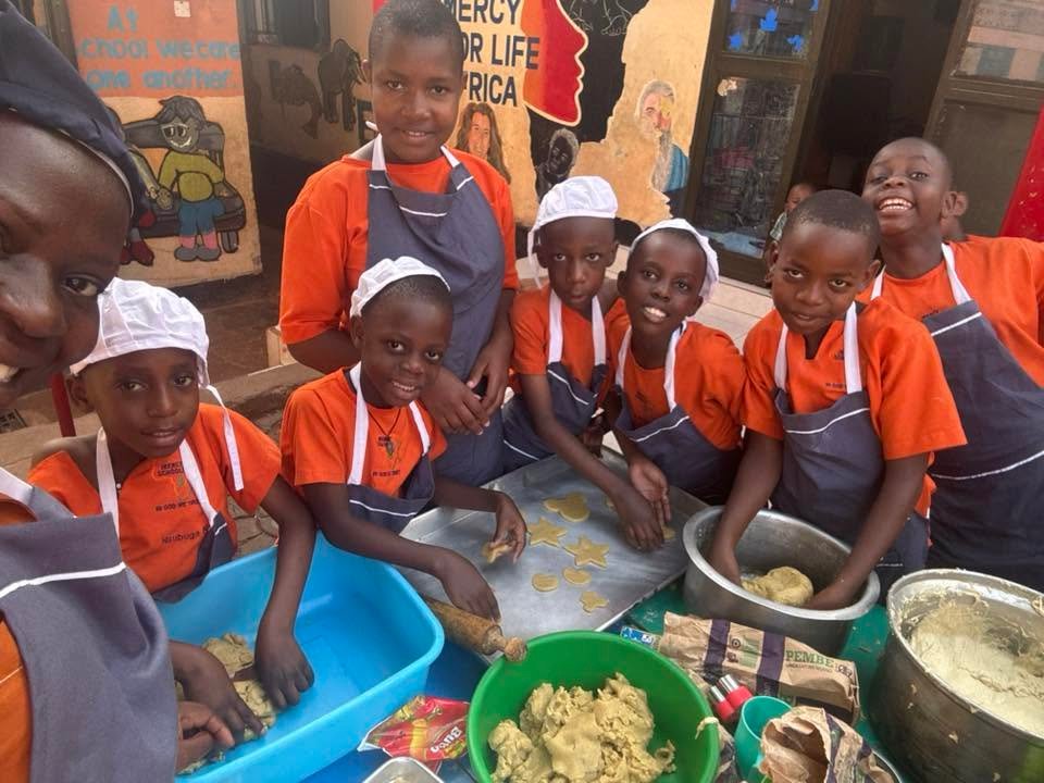 Mercy School children in orange shirts and aprons cut biscuit dough at a table