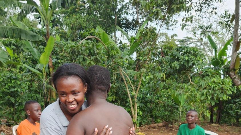 Director Nalubega Fausta embraces a neighbour during a home visit in Kampala