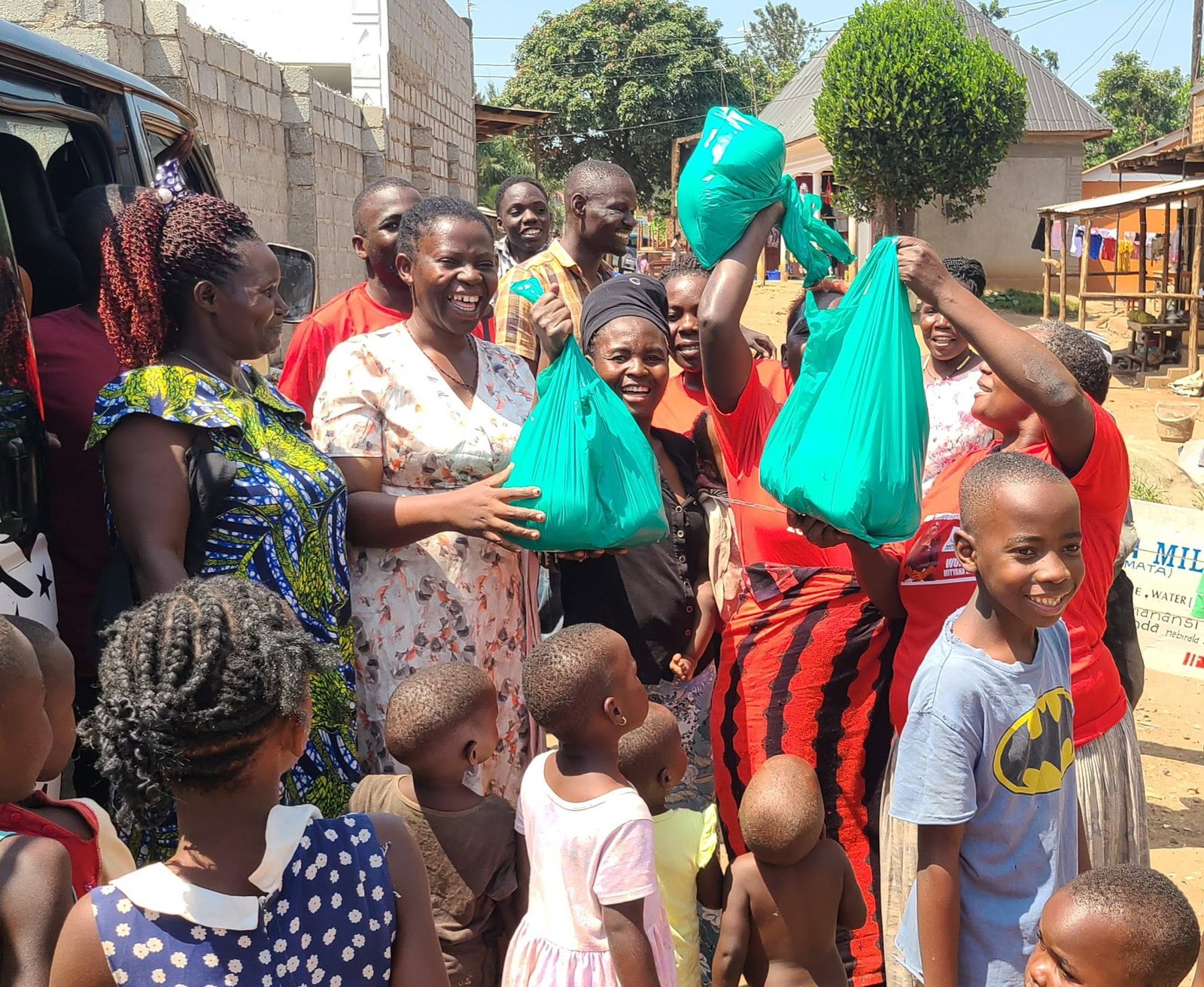 Women and children celebrate as Mercy For Life Africa staff hand out green food bags in a street