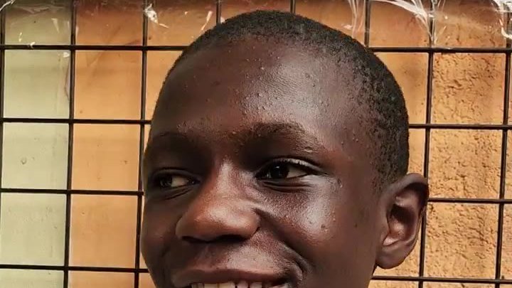 A schoolboy in a white uniform holds a handwritten letter to Mercy For Life Africa