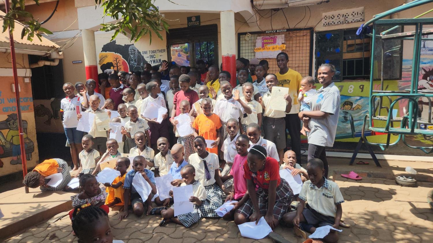 Pupils and staff of Mercy School Makindye gather in the courtyard holding letters